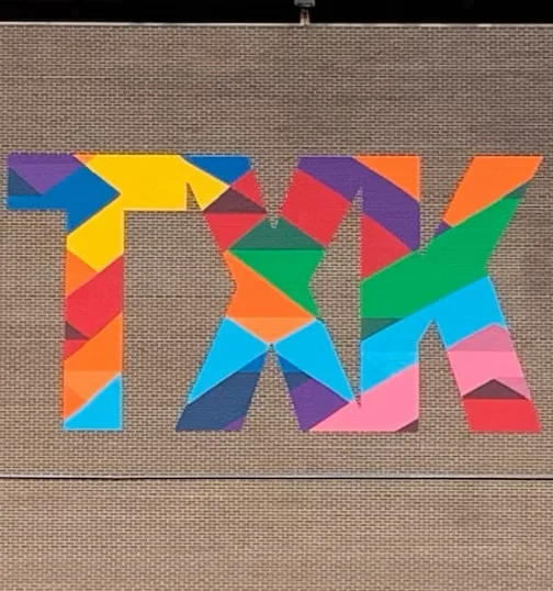 Bold geometric TXK mural in bright rainbow colors on a downtown Texarkana wall
